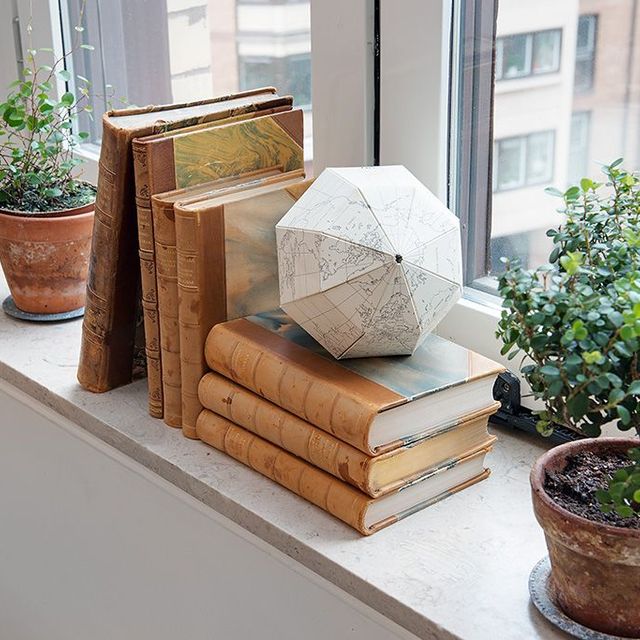 Böcker och krukor ståendes på en fönsterbänk i sten