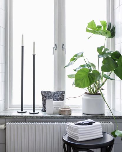 Ljusstake, Krukväxt och andra prydnadsföremål ståendes på en fönsterbänk i marmor